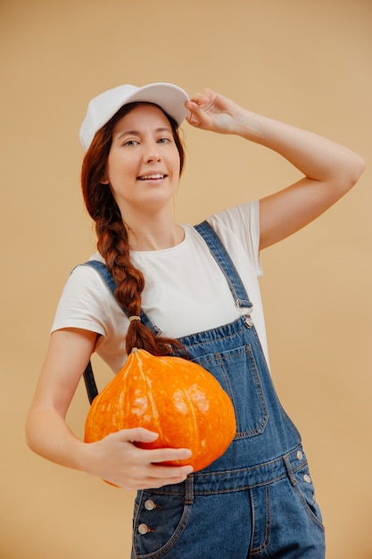 Woman in overalls on a yellow background with an autumn harvest of vegetables pumpkin