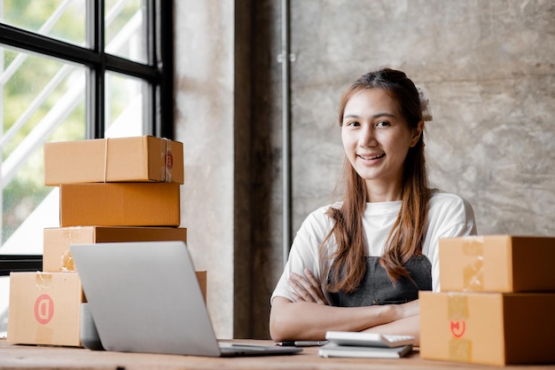 Woman owner of a startup company selling products online on an\
online store platform sending goods through a courier company\
business planning online selling and online shopping concepts