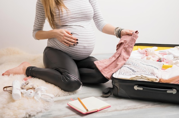 Photo woman packing baby clothes for hospital