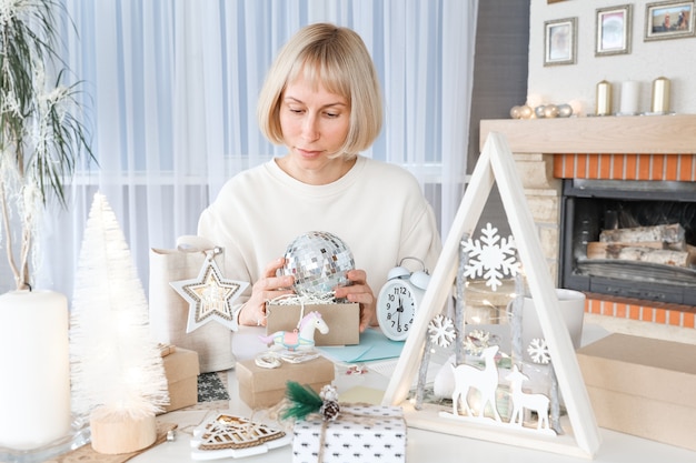 Photo woman packing christmas gifts, wrapping gift for christmas presents and new year. decorating holiday gift boxes. preparing for christmas. winter holidays, home decoration concept