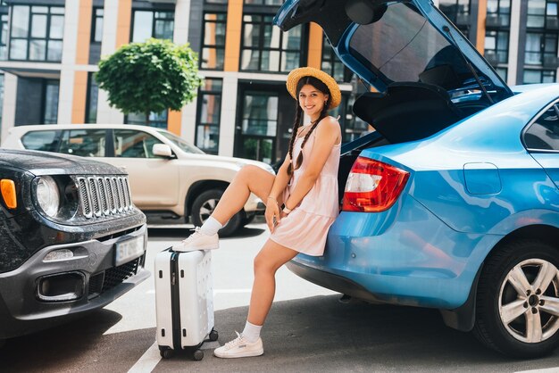 Woman packing her suitcase into luggage boot of the car