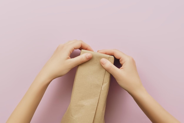 woman packing a parcel or gift in craft wrapping paper top view