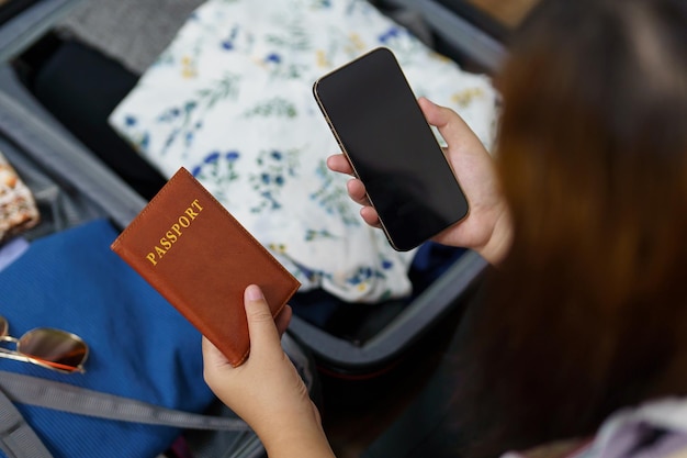 女性はスーツケースに荷物とパスポートを詰めて旅行の準備をします 新しい旅 荷物を詰める 旅行の計画を立てる 休暇を計画する