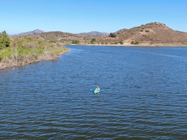 A woman paddles a kayak in a lake.