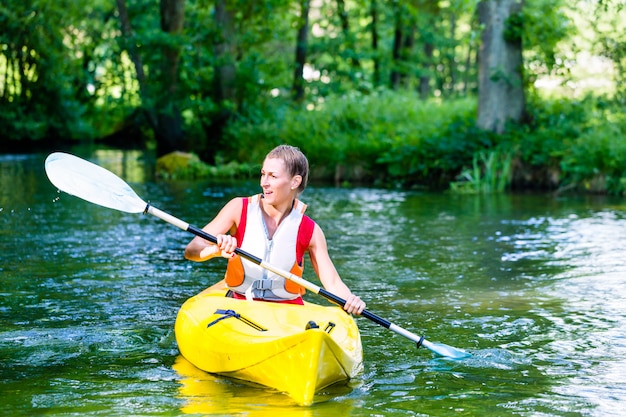 Donna che rema con la canoa sul fiume della foresta