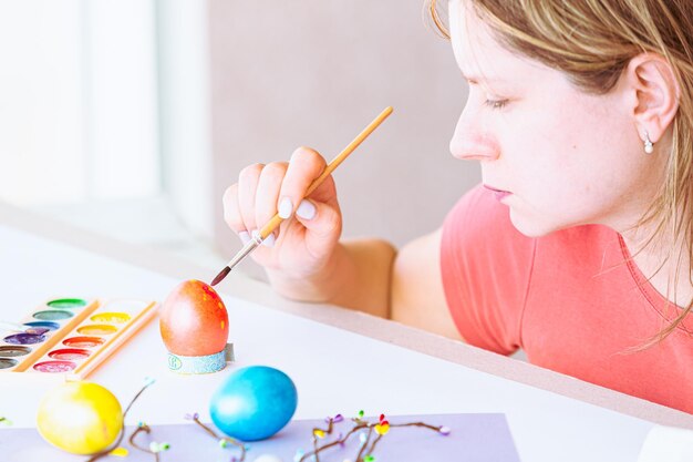 A woman painting easter eggs on a table