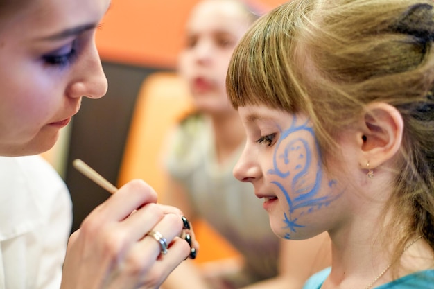 Woman painting face of kid outdoors baby face painting