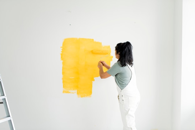 Woman painting her walls yellow