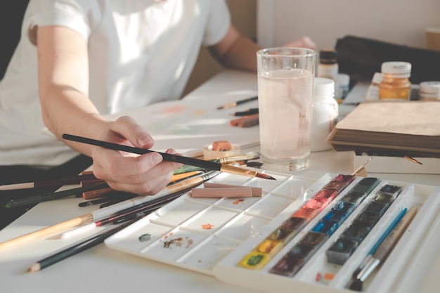 Woman painting a picture with a brush. Learning to draw at home.