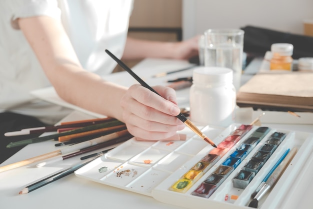 Woman painting a picture with a brush. Learning to draw at home.