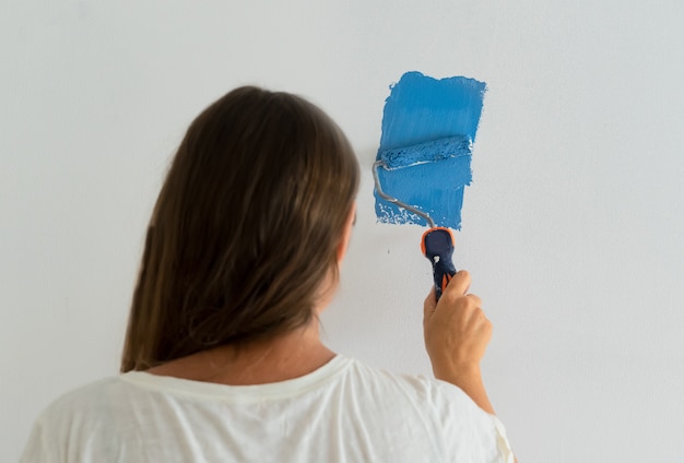 Woman painting wall in a blue colour