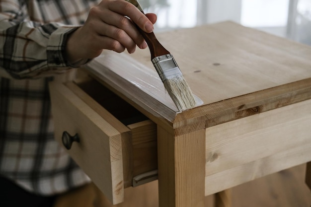 Woman painting a wooden bedside table with a brush