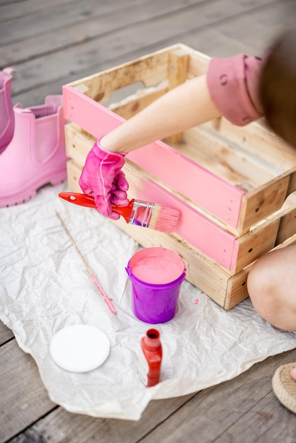 Woman painting wooden box in pink color DIY concept