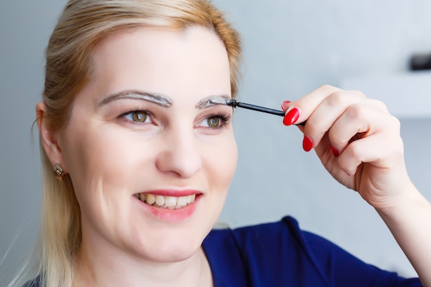 woman paints eyebrows at home closeup