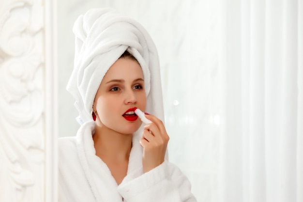 Woman paints her lips in hotel bathroom after shower