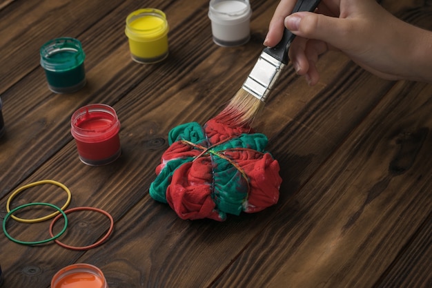 A woman paints her tie dye-style underwear in red and green. Staining fabric in tie dye style.