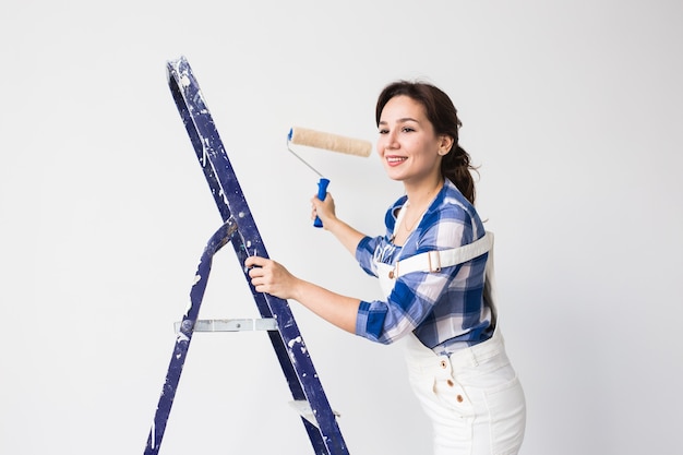 Женщина красит стену во время косметического ремонта.
