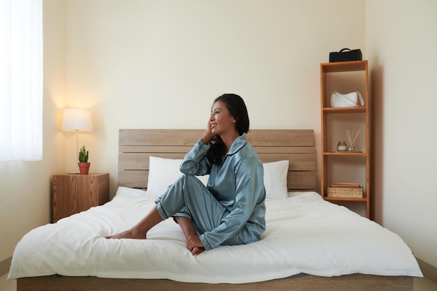 Woman in Pajama Sitting on Bed