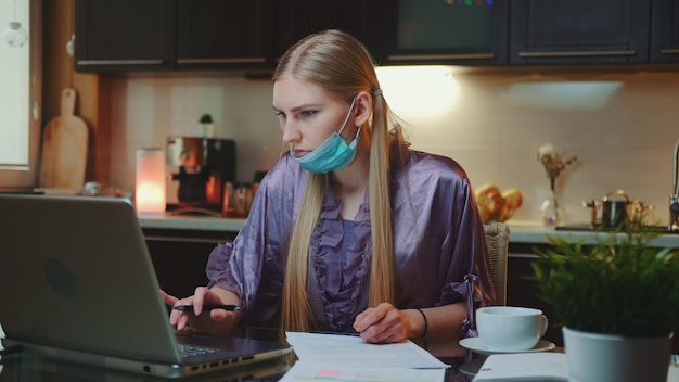 Woman in pajama and with medical mask signing documents