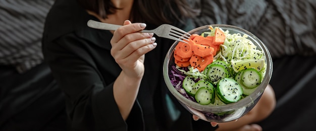 新鮮なベジタリアン野菜のサラダとベッドでパジャマを着た女性。