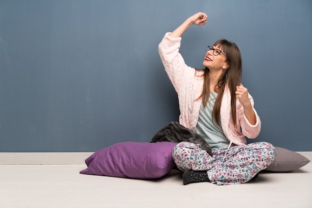 Woman in pajamas on the floor celebrating a victory