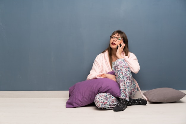 Woman in pajamas on the floor keeping a conversation with the mobile phone