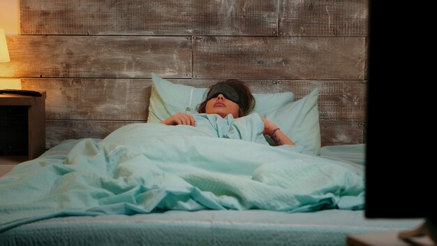 Woman in pajamas having a nightmare while sleeping with eye mask.