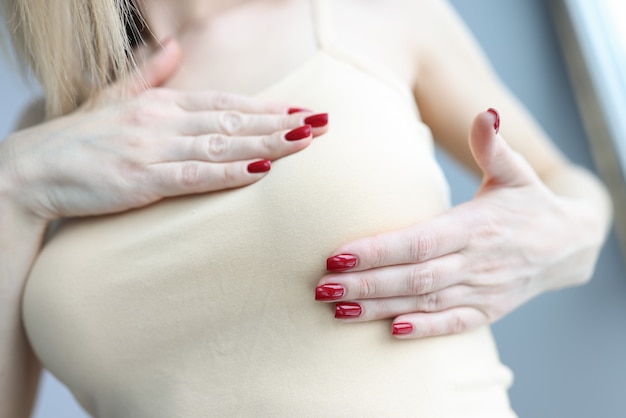 Woman palpating her breasts with hands closeup