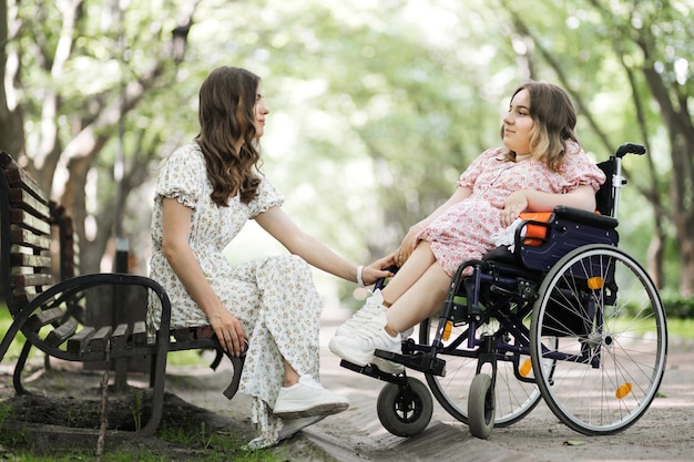 Woman at park holding friend's hand who using wheelchair