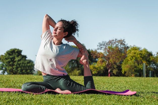 Woman in a park making pigeon pose yoga in a park