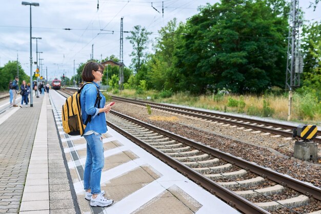 woman passenger waiting for commuter train at station outdoor platform rail transport passenger transportation destination journey tourism travel trip people concept
