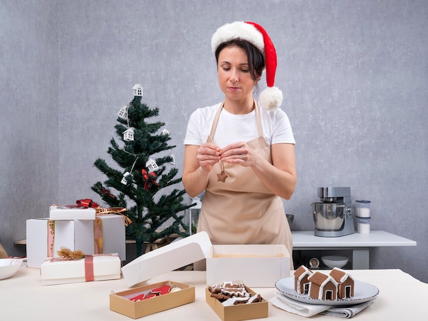 女性のパティシエがクリスマスのお菓子をプレゼントに詰めています。ジンジャーブレッドクッキー。