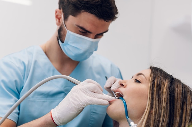 Woman patient in dental clinic being examined by a male\
dentist