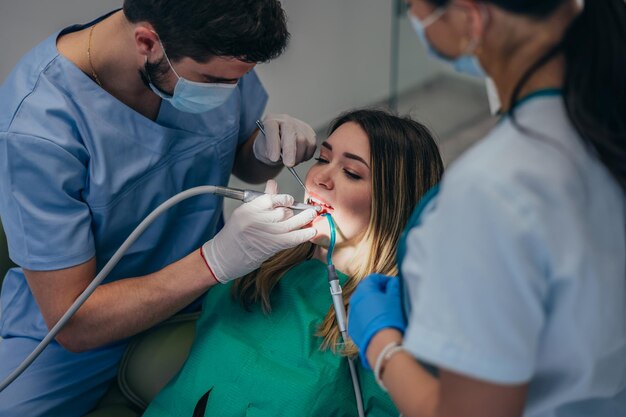 Woman patient in dental clinic being examined by a male dentist