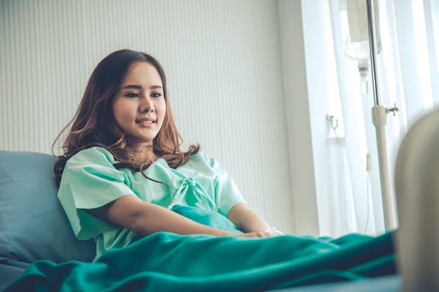 Пациент женщина в зеленой рубашке, лежа на больничной койке кровати.