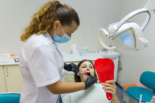 Woman patient looking in mirror at the teeth