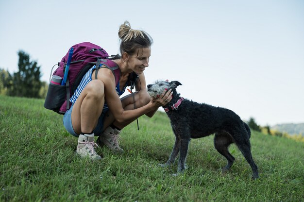 ハイキングに彼女の犬をなでる女性