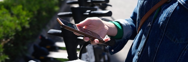 Woman paying rent of electric scooter using mobile app on\
street using smartphone to pay for