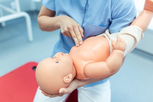 Woman performing CPR on baby training doll with one hand compression First Aid Training  Cardiopulmonary resuscitation First aid course on cpr dummy