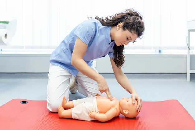 Woman performing cpr on baby training doll with one hand\
compression first aid training cardiopulmonary resuscitation first\
aid course on cpr dummy