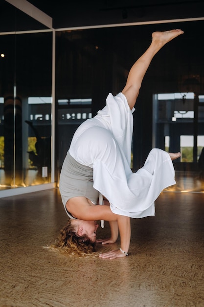 Una donna che esegue esercizi di yoga sulla sua testa in palestra