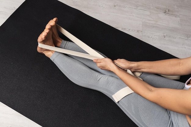 A woman performs an exercise to stretch her leg muscles with the help of straps