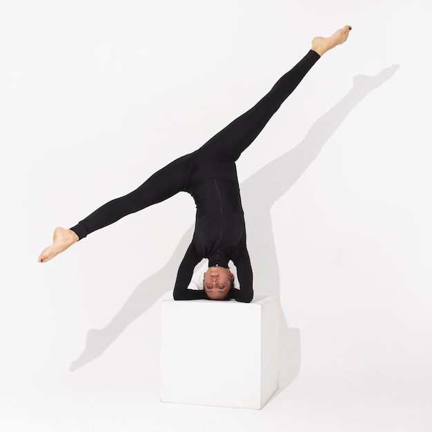 Donna esegue l'esercizio salamba shirshasana posa asana invertita o headstand si erge su un cubo