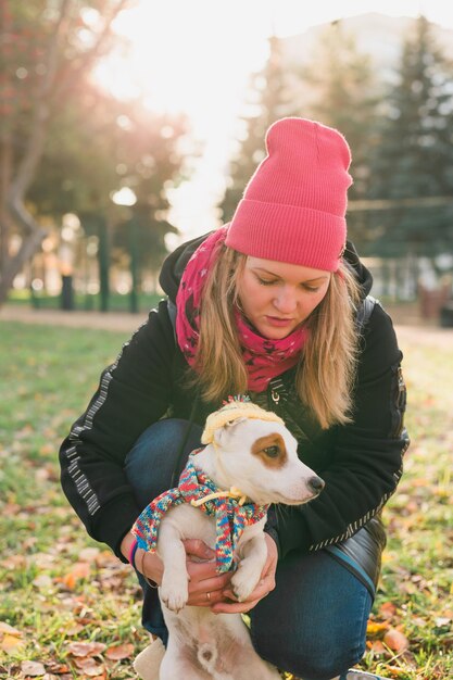 Donna proprietario dell'animale domestico che cammina cane jack russell terrier in abiti divertenti su strada all'aperto cura degli animali concep