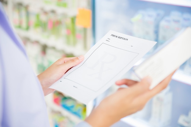 Woman pharmacist holding prescription checking medicine in pharmacy 