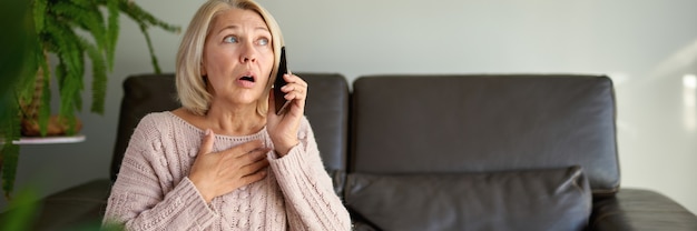 Woman in a phone call sitting on a sofa in the living room in a house