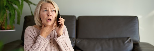 Woman in a phone call sitting on a sofa in the living room in a house