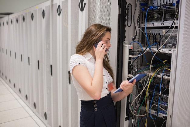 Woman on the phone holding tablet pc checking the servers