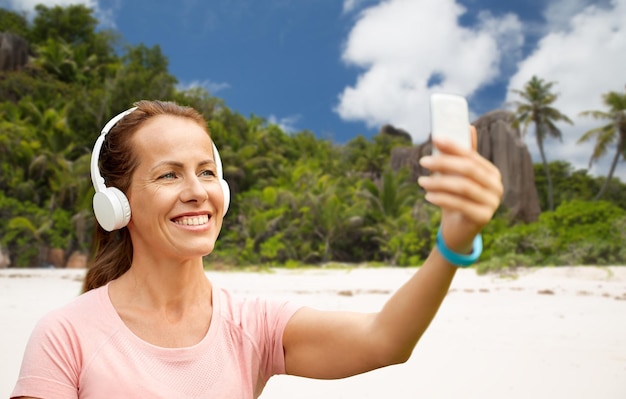 woman in phones takes selfie by cellphone on beach