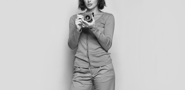 Woman photographer crop view holding photo camera in hands beige background photography